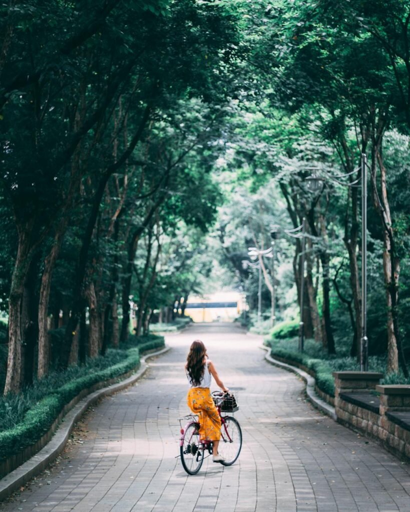 woman in orange dress riding bicycle on road