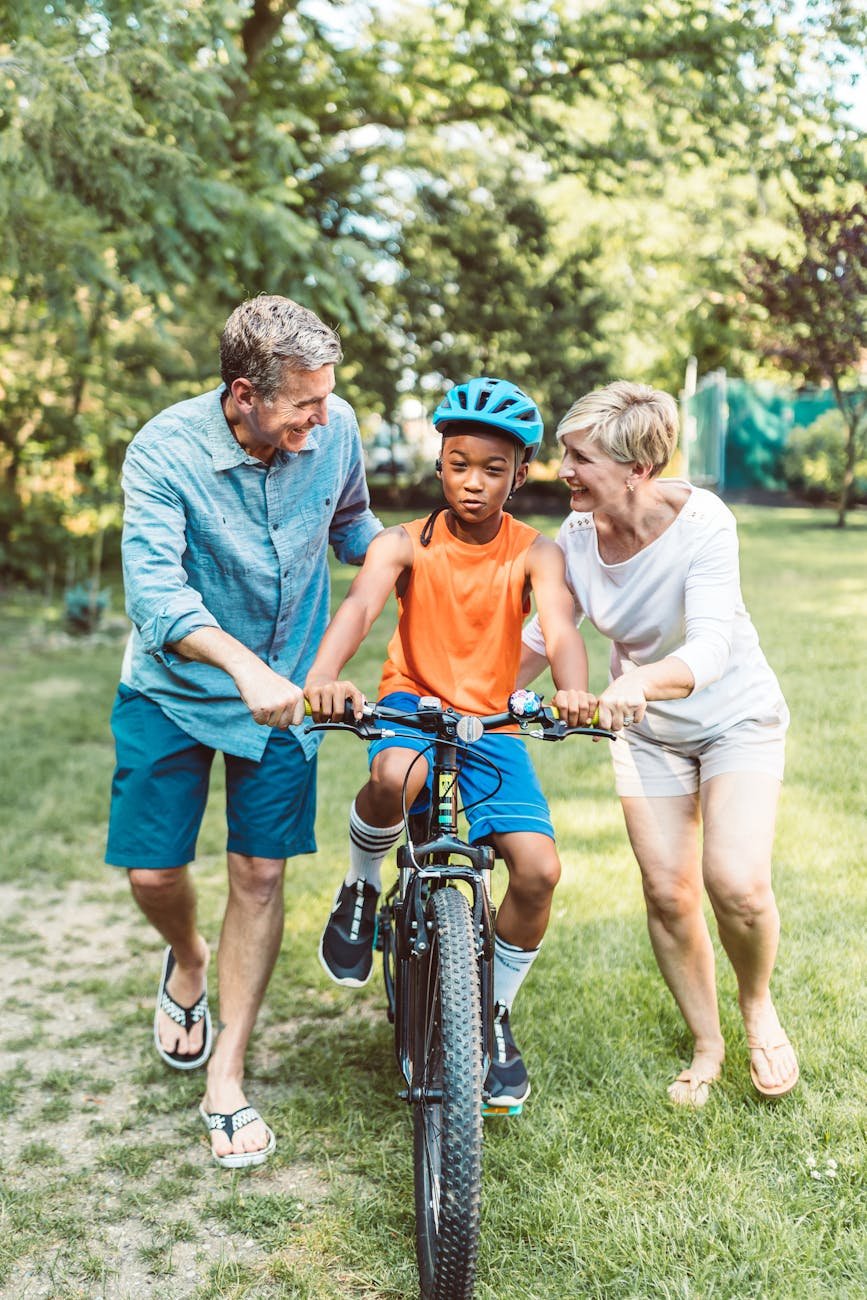 parents guiding their child to ride a bike