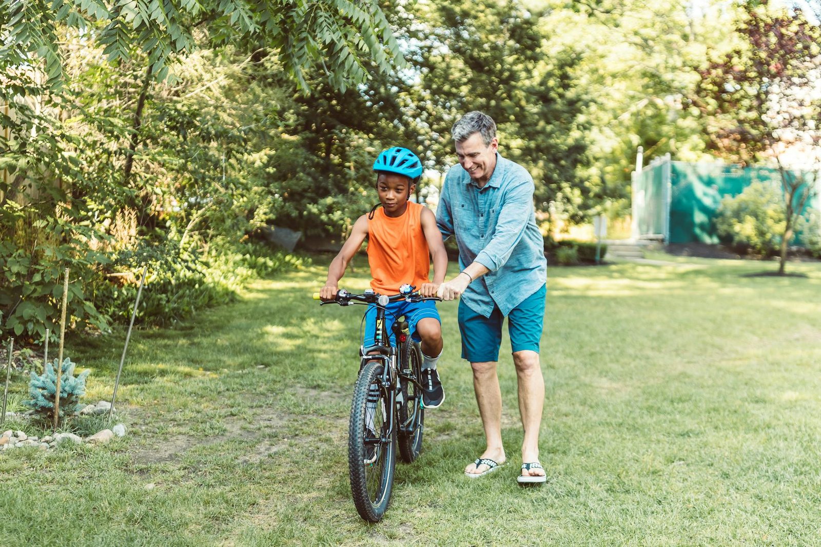 father guiding his child to ride a bike